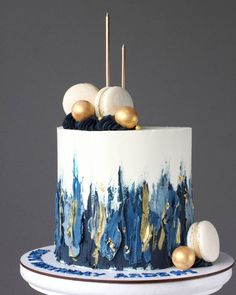 a white and blue cake with gold decorations on it's top, sitting on a plate