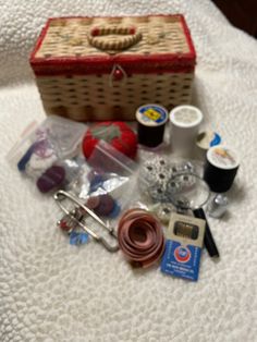 the contents of a sewing kit laid out on a white blanket with scissors and thread