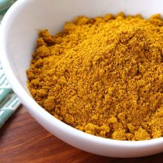 a white bowl filled with yellow powder on top of a wooden table