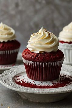 red velvet cupcakes with white frosting and sprinkles on plates