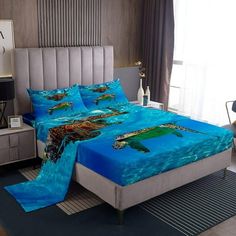 a bed with blue sheets and sea turtles on it in a bedroom area next to a window