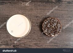 a glass of milk next to a chocolate cookie on a wooden table top view from above