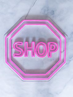 a neon sign with the word shop on it in pink and white letters that spell out