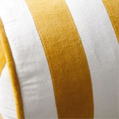 a yellow and white striped pillow sitting on top of a bed