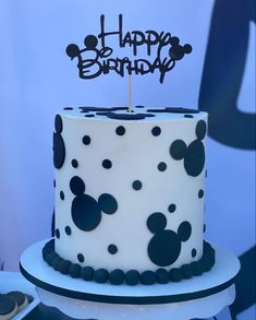 a white and black cake with mickey mouse decorations on it's top is sitting on a table