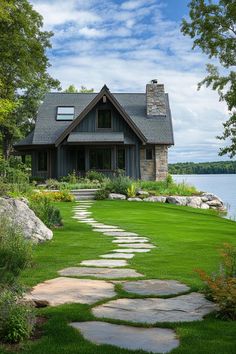 a stone path leads to a house on the water's edge, surrounded by lush green grass