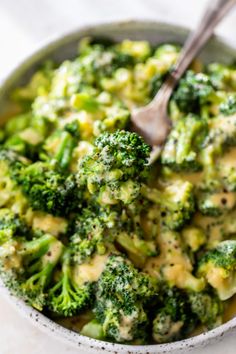 a bowl filled with broccoli and cheese on top of a white tablecloth