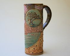 a brown and green ceramic mug sitting on top of a white table next to a wall