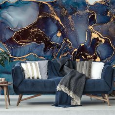 a blue couch sitting in front of a large painting on the side of a wall