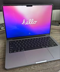 an open laptop computer sitting on top of a wooden table with the word hello written on it