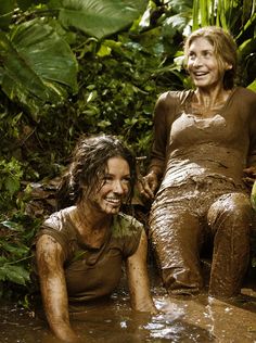 two women are sitting in the mud and smiling