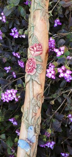 an arm with flowers and butterflies on it next to purple flowers in front of a bush