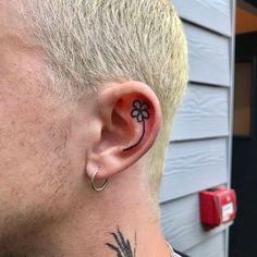 a man with a small flower tattoo on his left side of the ear, behind his ear