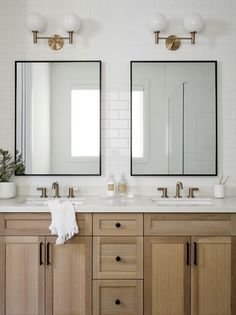 two bathroom sinks with mirrors and lights above them