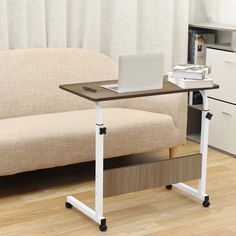 a laptop computer sitting on top of a wooden desk next to a white couch in a living room