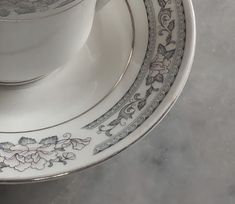 a white cup and saucer sitting on top of each other in front of a marble table