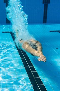 a man swimming in a pool with his back turned to the camera and head above water