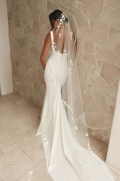 a woman in a wedding dress with a veil over her head and flowers on it