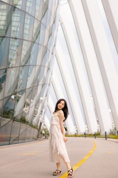 a woman standing in front of a building with large glass windows and yellow lines on the ground