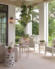 a living room filled with white furniture and lots of plants on the windowsills