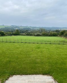 a grassy field with a wooden fence in the middle