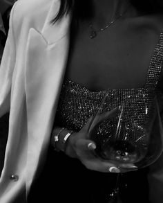 black and white photograph of a woman holding a wine glass in her right hand while wearing a jacket