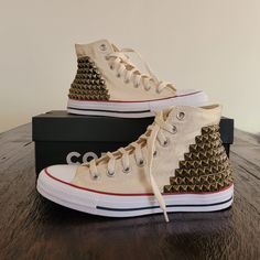 Custom Studded, Brand New in Box, Authentic Converse Shoes ** This listing is for both outer sides of each shoe studded, only (for all 4 sides studded, please inquire for custom order listing) ** - Off White Natural Ivory Converse High Top Shoes. Brass Studs.  - Each one of these bad boys is meticulously hand studded and Made to Order.  - Studs are secured through fabric, not glue. Lined for comfort.  Please message me if you are interested in additional shoe colors, stud colors or size options which may not be listed, Custom Orders are welcomed.   -------------------------------------------------------------------------- Please understand returns or exchanges are not accepted on any studded shoe items as they are hand made to order, but I am always happy to work with any problems or conce Ivory Converse, Converse Shoes High Top, Upcycle Shoes, Studded Converse, Cute Converse Shoes, Cute Converse, Converse High Top, Sneakers Box, Studded Sneakers