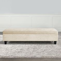 a beige bench sitting on top of a white rug