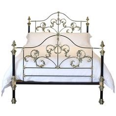 a metal bed frame with white sheets and decorative designs on it's headboard