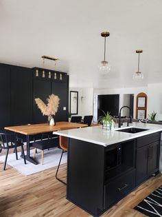 a kitchen with black cabinets and an island in the middle is seen from across the room