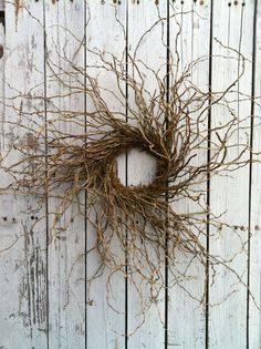 a dried twig wreath hanging on a white wooden fence with the word love written in it