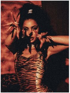 a woman in a tiger print dress holding her hands up to her face and posing for the camera