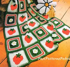 a crocheted blanket with apples and flowers on it