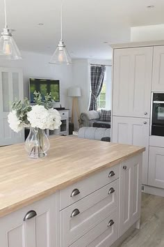 a large kitchen with white cabinets and wood counter tops, along with an island in the middle