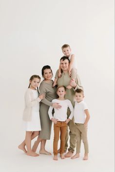 a group of people standing next to each other in front of a white background with one person holding the child