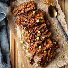 grilled pork chops with sauce and green onions on parchment paper next to spoon