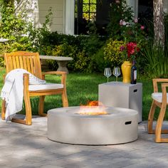 a fire pit sitting on top of a patio next to two chairs and a table