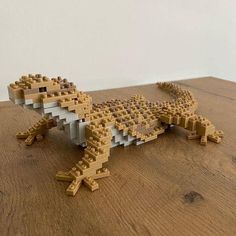 a wooden table topped with a lego model of a lizard