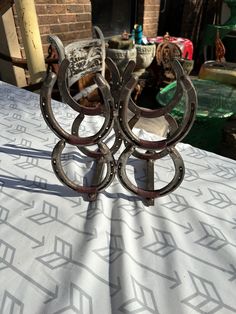 two metal objects sitting on top of a white tablecloth covered table in front of a brick building