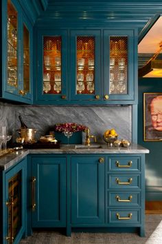 a kitchen with blue cabinets and marble counter tops, gold trimmings and brass knobs