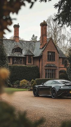 a black sports car parked in front of a large brick house with chimneys on the roof