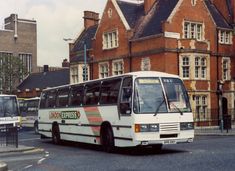 a white bus driving down a city street next to tall brick buildings on either side of the road