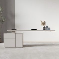 a white table with two vases on it and a plant in the corner next to it