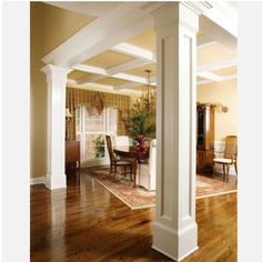 an open living room with wooden floors and white columns