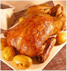 a roasted turkey with potatoes and gravy sits on a plate next to a mug