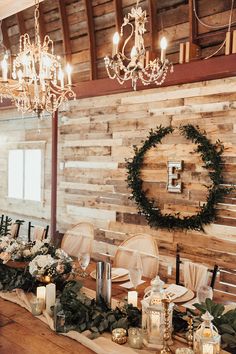 the table is set with candles, flowers and greenery