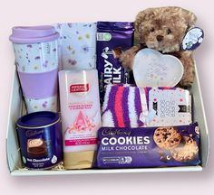 a teddy bear sitting in a box filled with cookies, milk, and other items