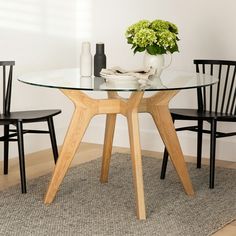 a glass table with two chairs around it and a vase filled with flowers on top