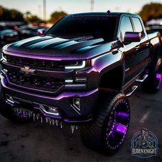 a black truck with purple lights on it's hood is parked in a parking lot