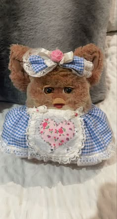 a brown teddy bear wearing a blue and white dress with a heart on it's chest